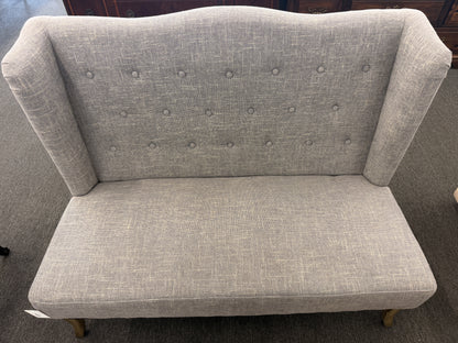Gray upholstered loveseat on a carpeted floor