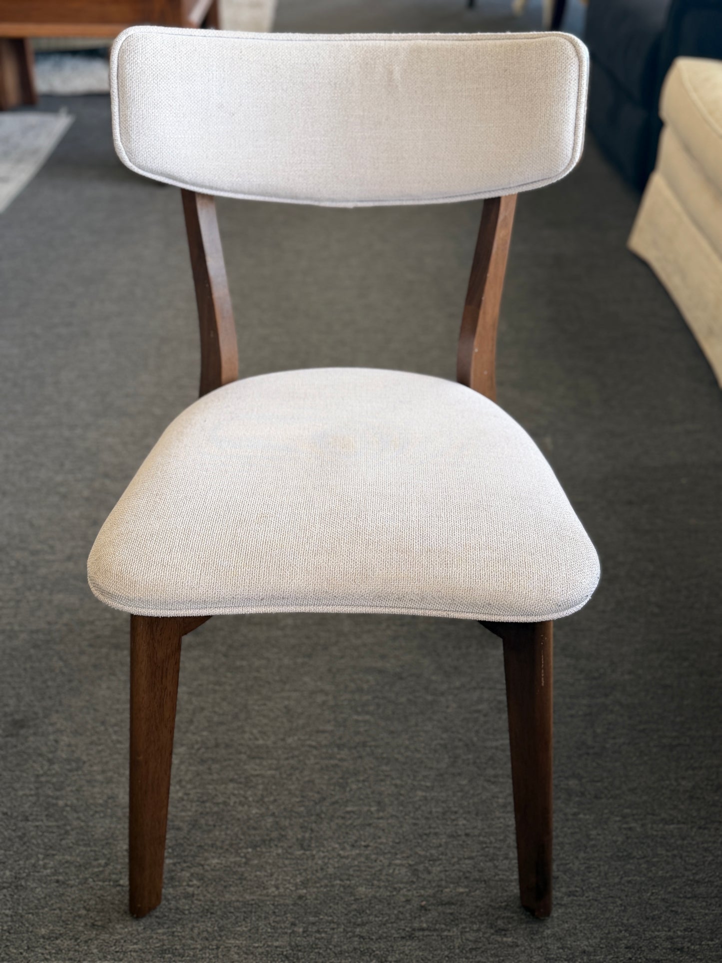 Beige chair with wooden legs on a gray floor