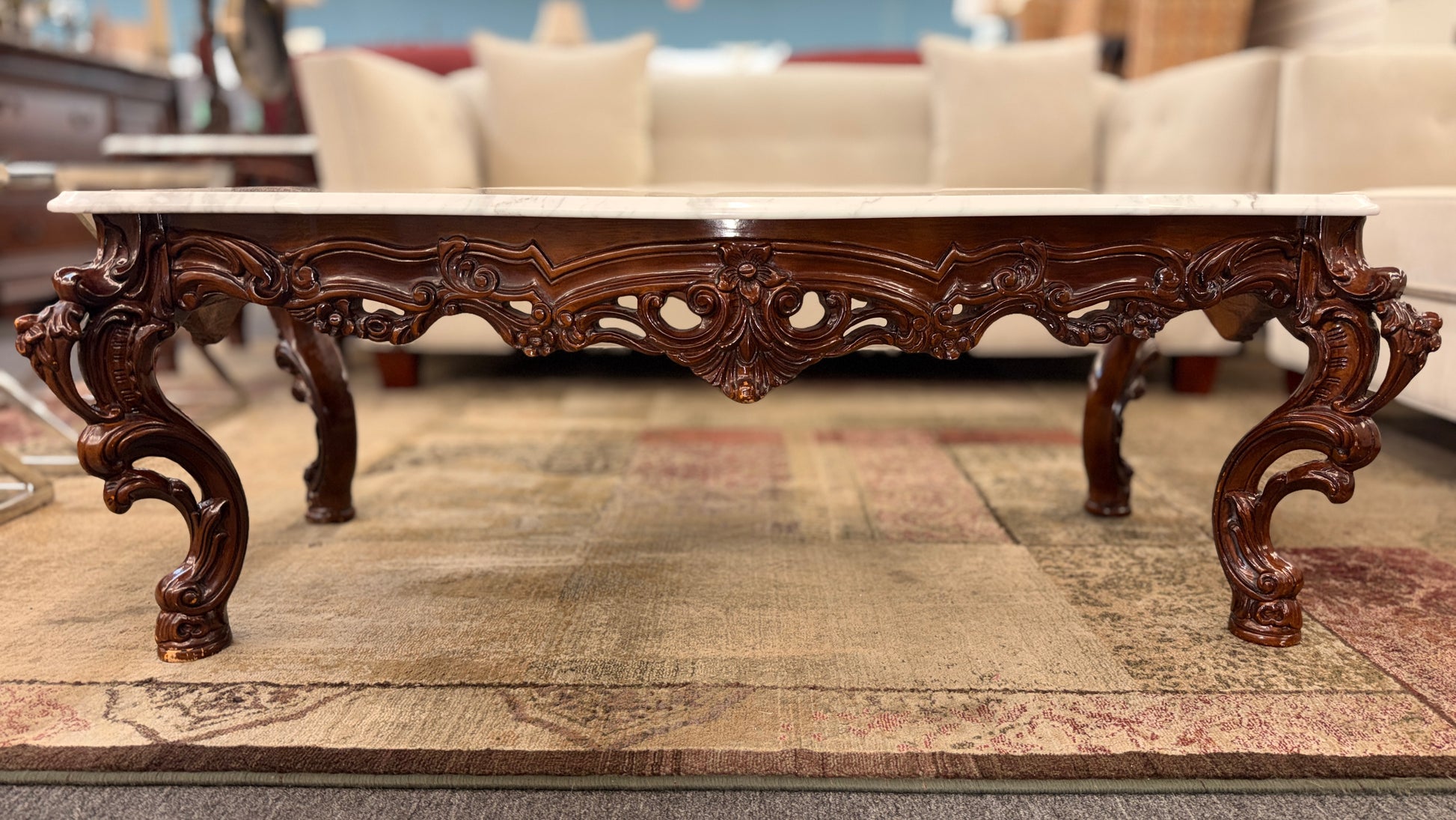 Carved wooden coffee table with marble top in a living room setting