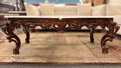 Carved wooden coffee table with marble top in a living room setting