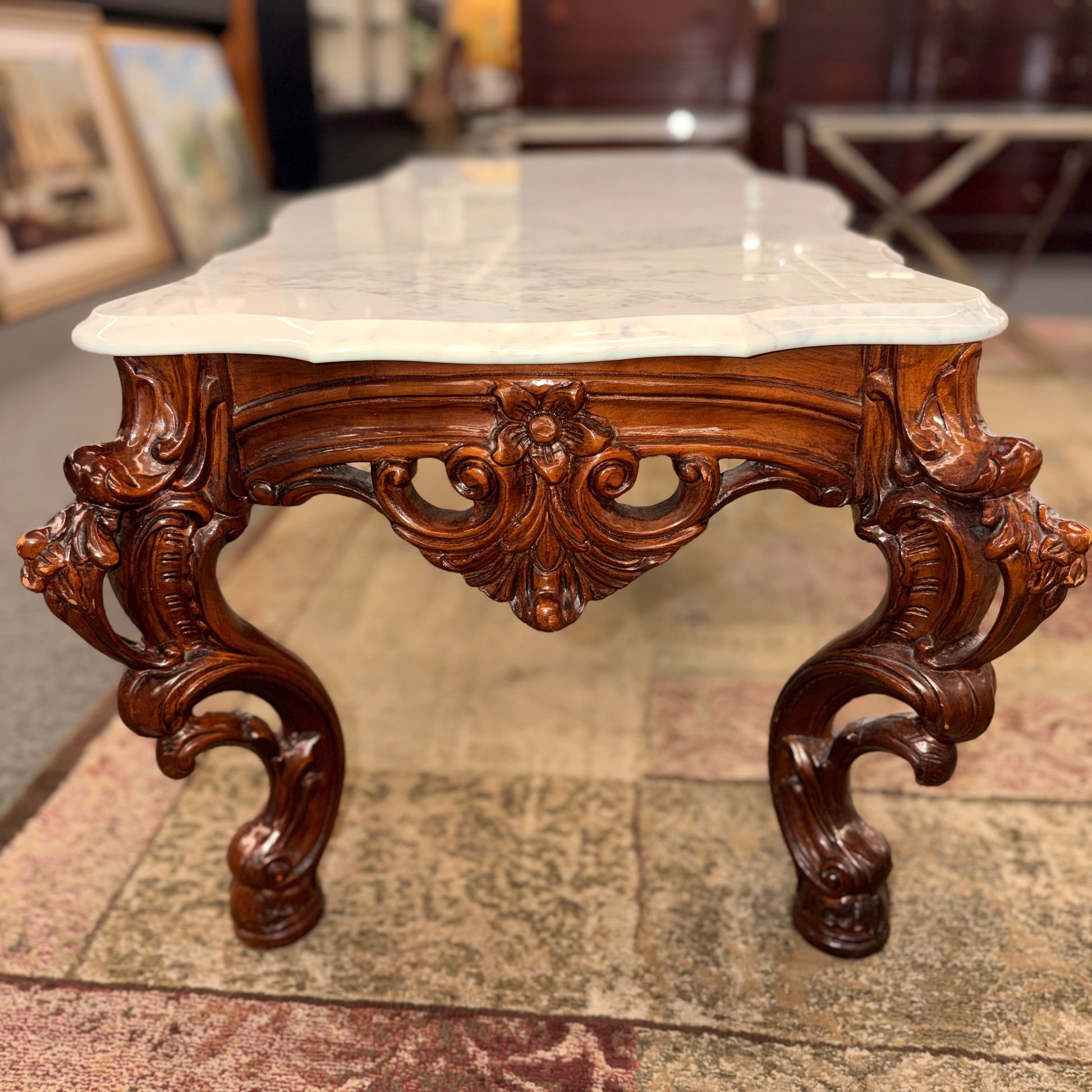 Carved wooden table with marble top on a patterned rug