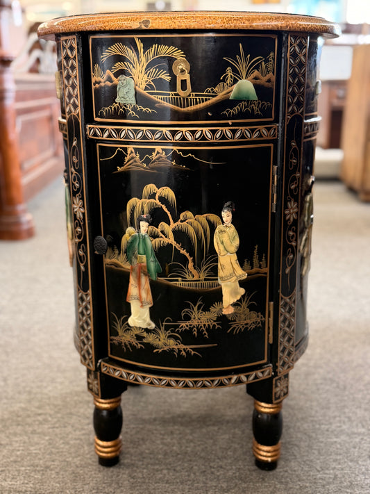 Decorative black cabinet with gold accents and intricate designs on a carpeted floor.