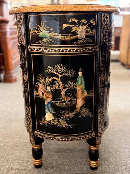 Decorative side table with black and gold chinoiserie design on a carpeted floor.