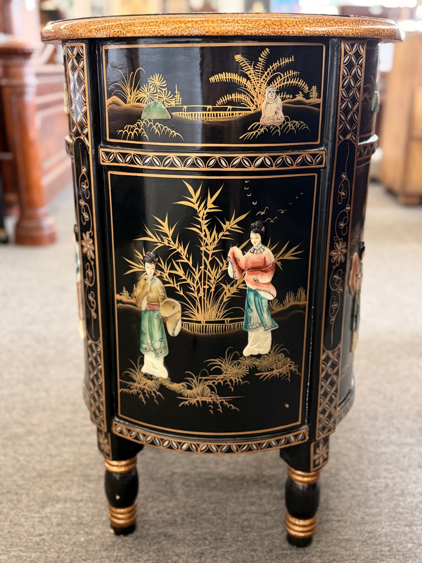 Decorative side table with black and gold chinoiserie design featuring people and landscape.