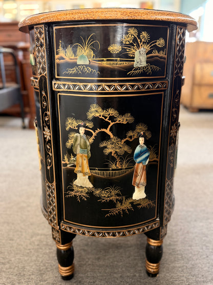 Decorative side table with intricate designs and figures on a carpeted floor.