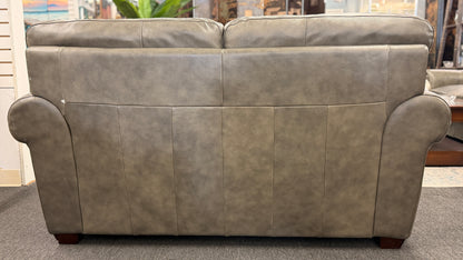 Gray leather sofa in a room with a window and plants.