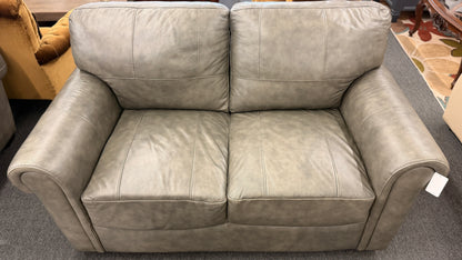 Beige leather sofa in a store setting with a price tag.