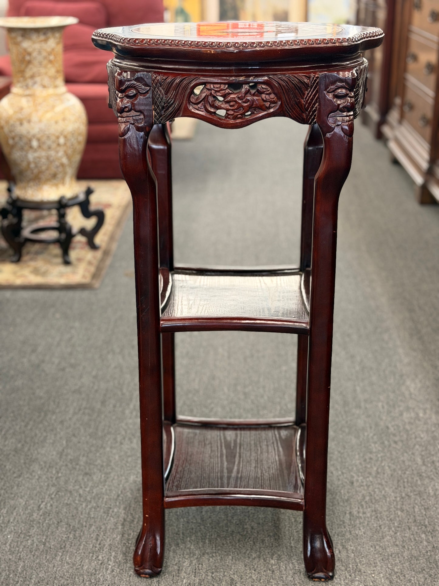 Decorative wooden side table with intricate carvings in a room setting.
