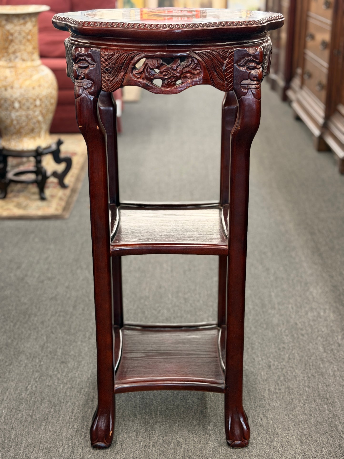 Carved wooden plant stand on a carpeted floor
