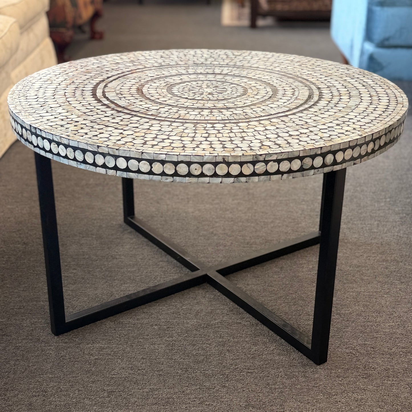 Round mosaic table with decorative pattern on a carpeted floor