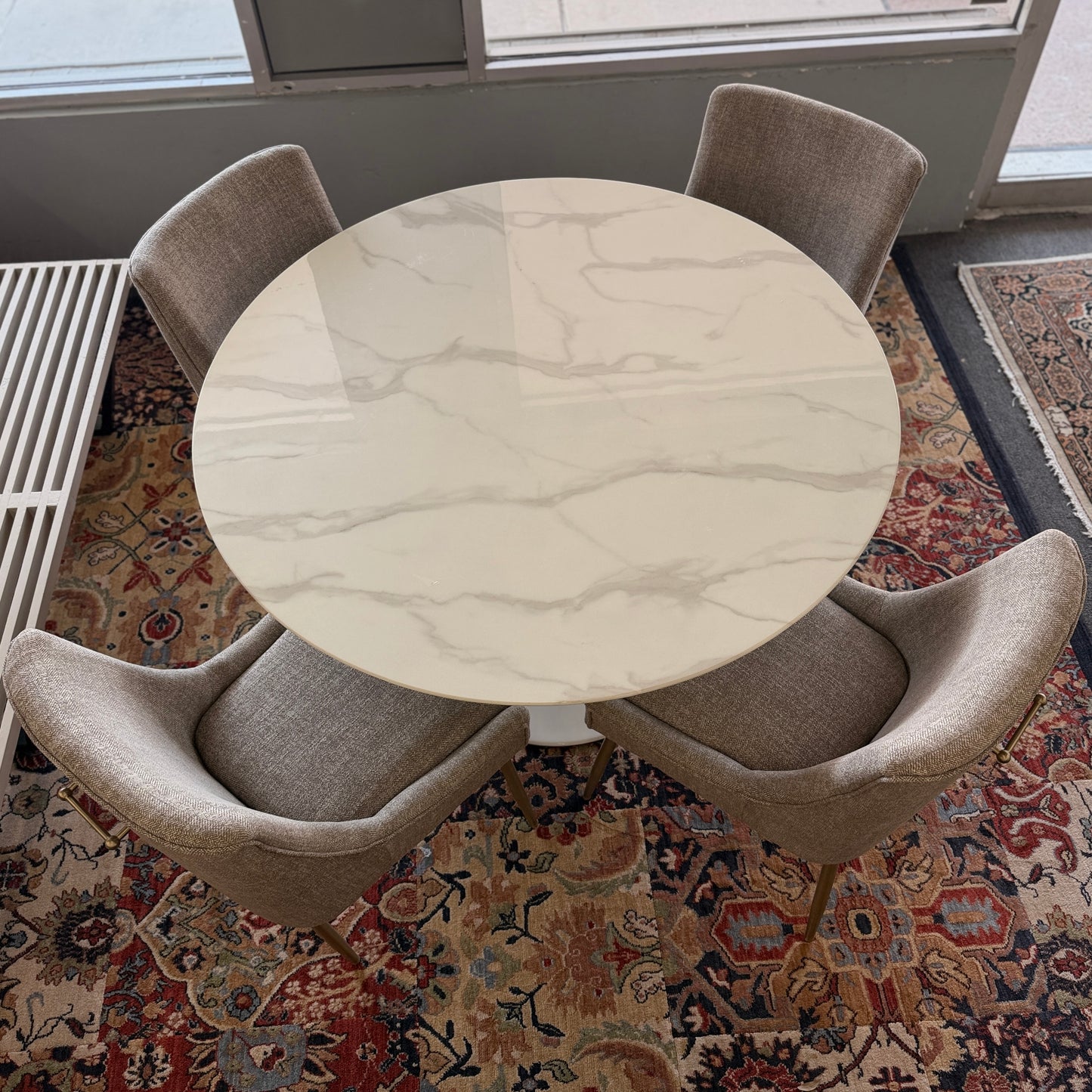 Round marble table with four chairs on a patterned rug