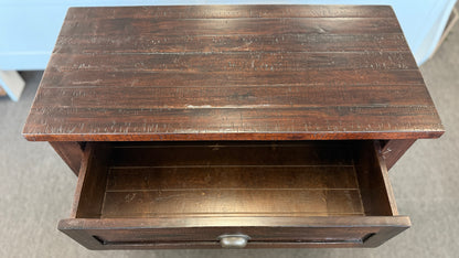 Wooden table with a drawer on a gray floor