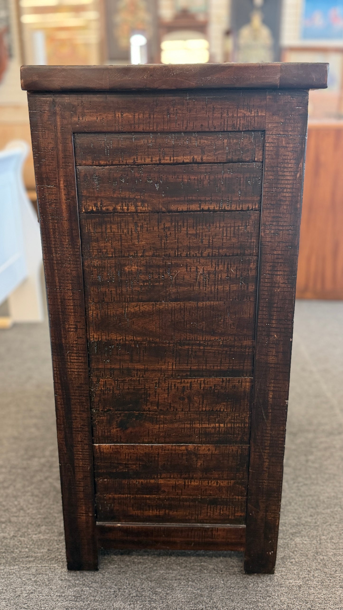 Dark wooden cabinet with a textured surface on a gray floor.