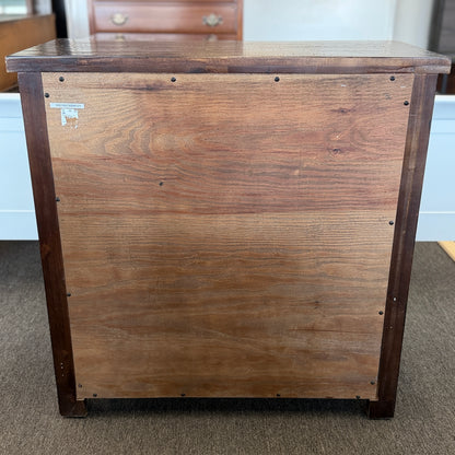 Wooden cabinet with a visible brand label on a carpeted floor.