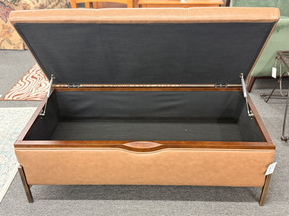 Brown leather storage bench with open lid on a carpeted floor