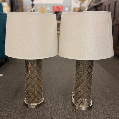 Two table lamps with textured metal bases and beige lampshades on a carpeted floor.