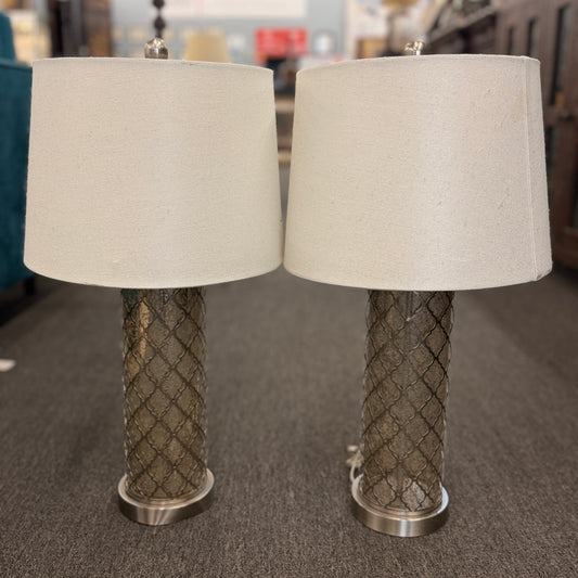 Two table lamps with textured metal bases and beige lampshades on a carpeted floor.