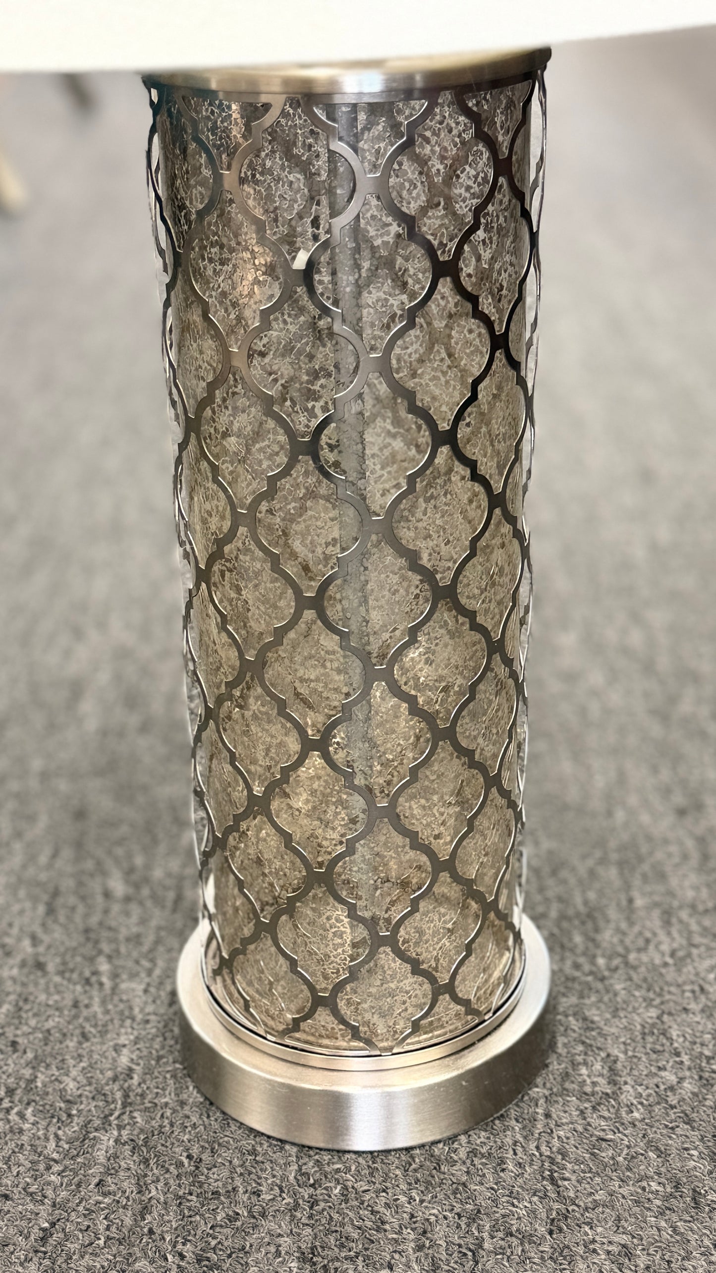 Decorative cylindrical object with metallic top and textured base on a gray surface