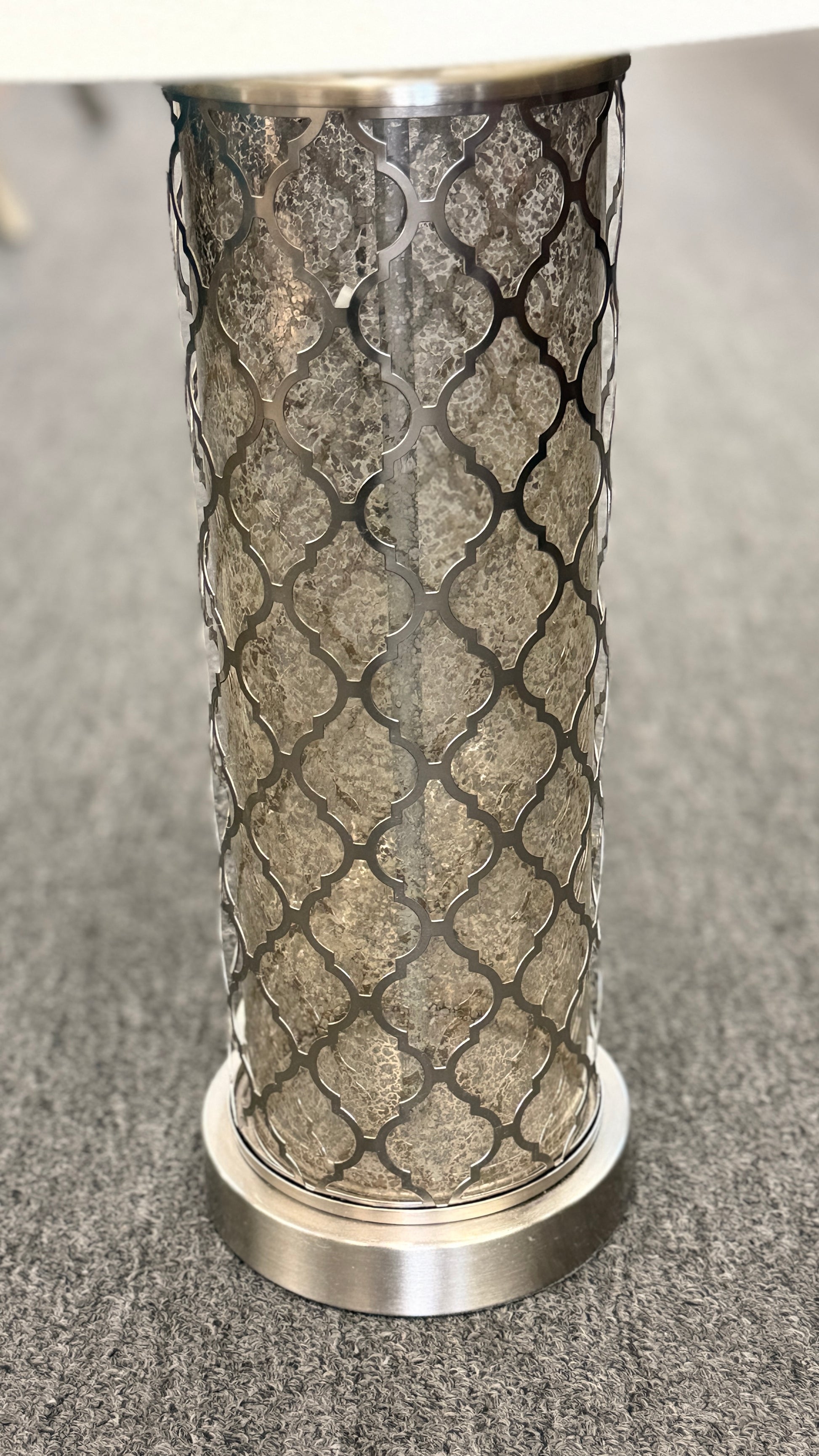 Decorative cylindrical object with metallic top and textured base on a gray surface