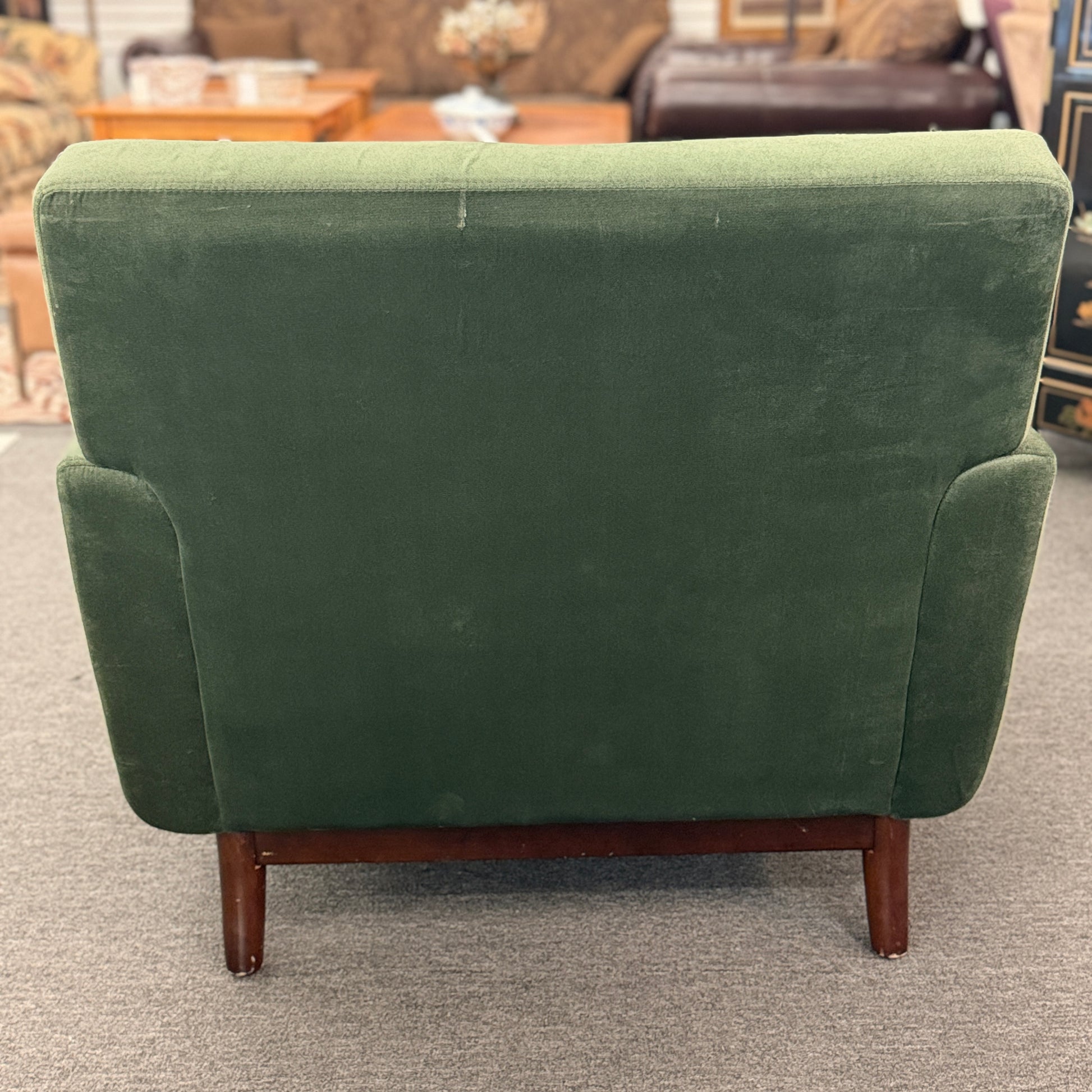 Green upholstered chair with wooden legs in a room setting