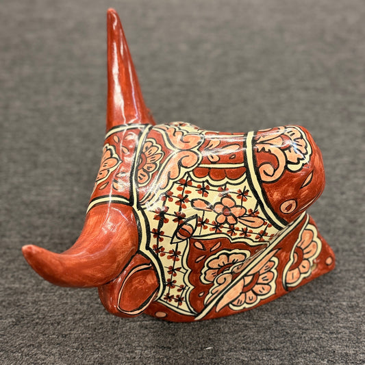 Decorative cow head sculpture with intricate patterns on a gray background