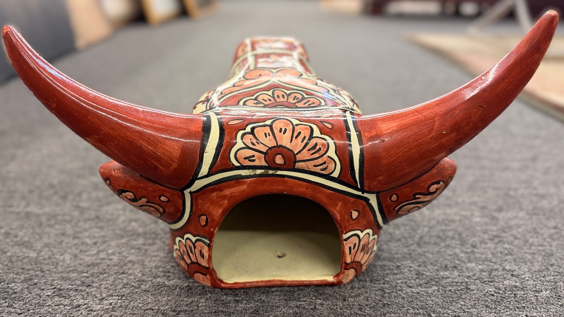 Decorative ceramic bull head with floral patterns on a gray surface