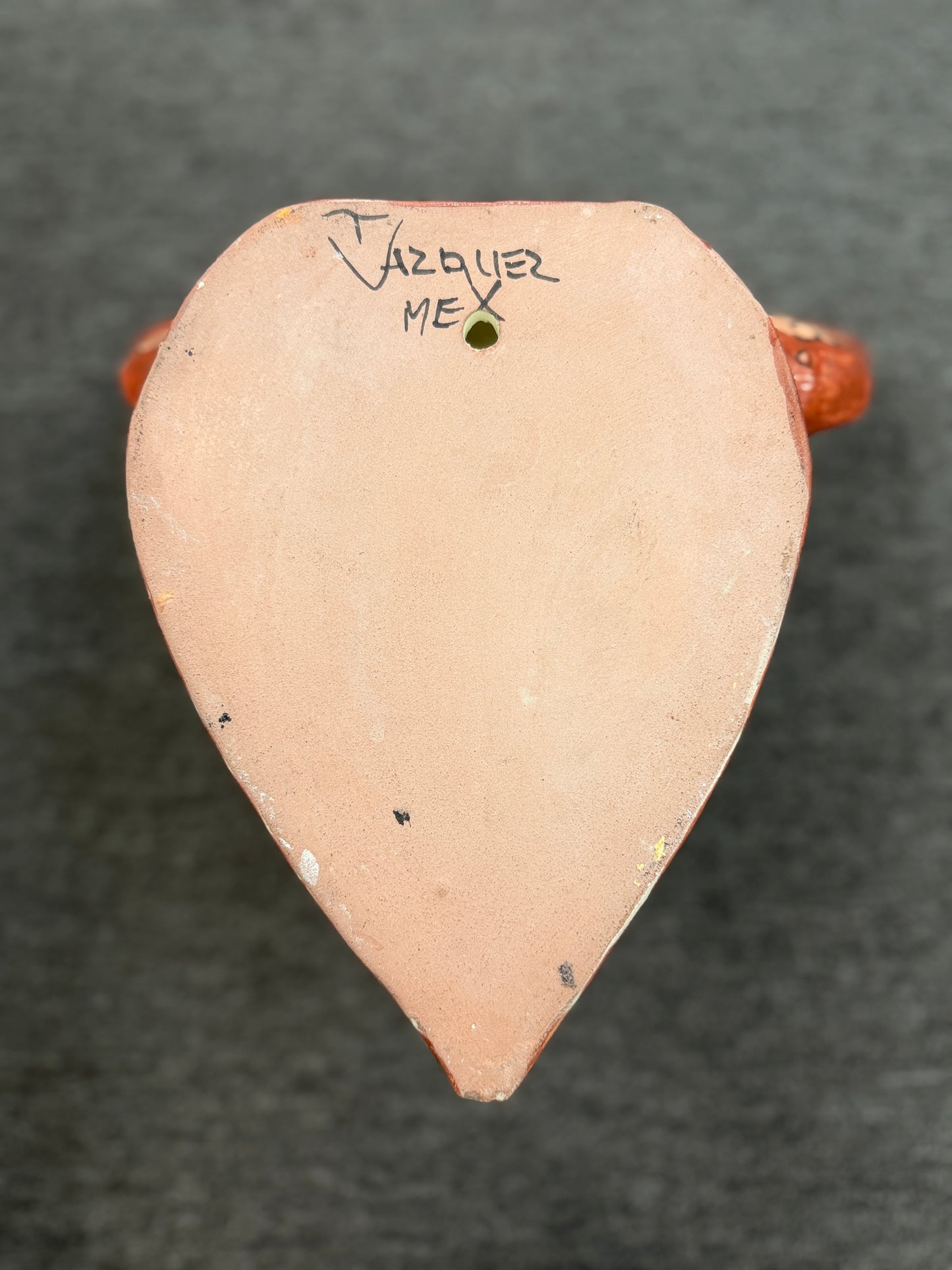 Small ceramic object with 'Vazquez' and 'MEX' inscription on a dark background