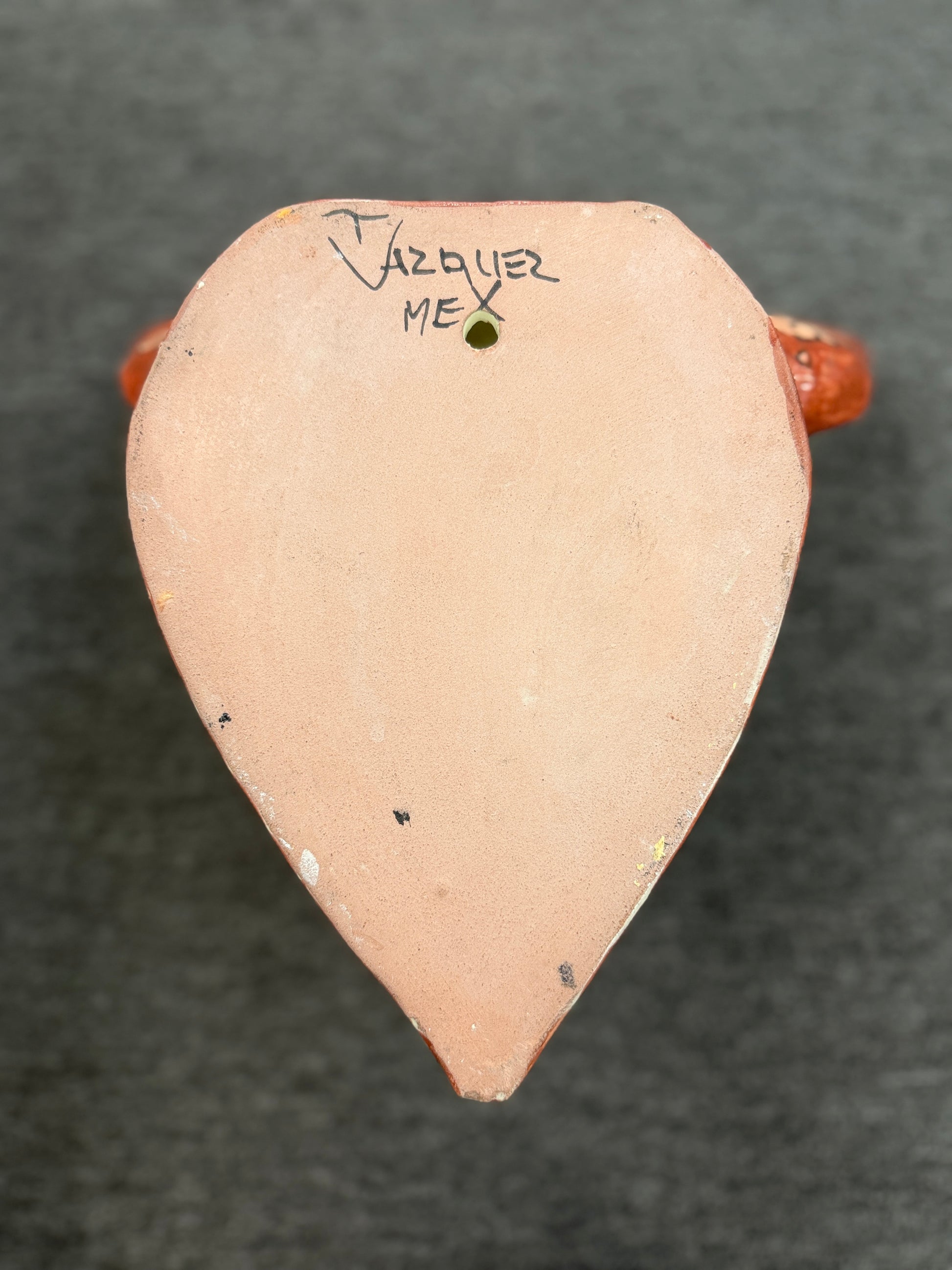 Small ceramic object with 'Vazquez' and 'MEX' inscription on a dark background