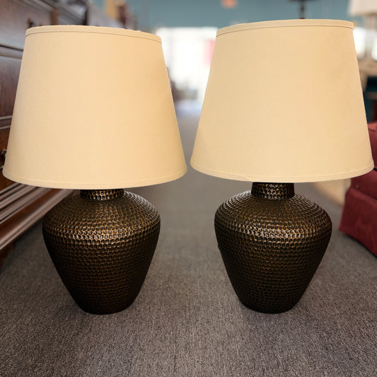 Two beige lampshades with metal fixtures on a gray background