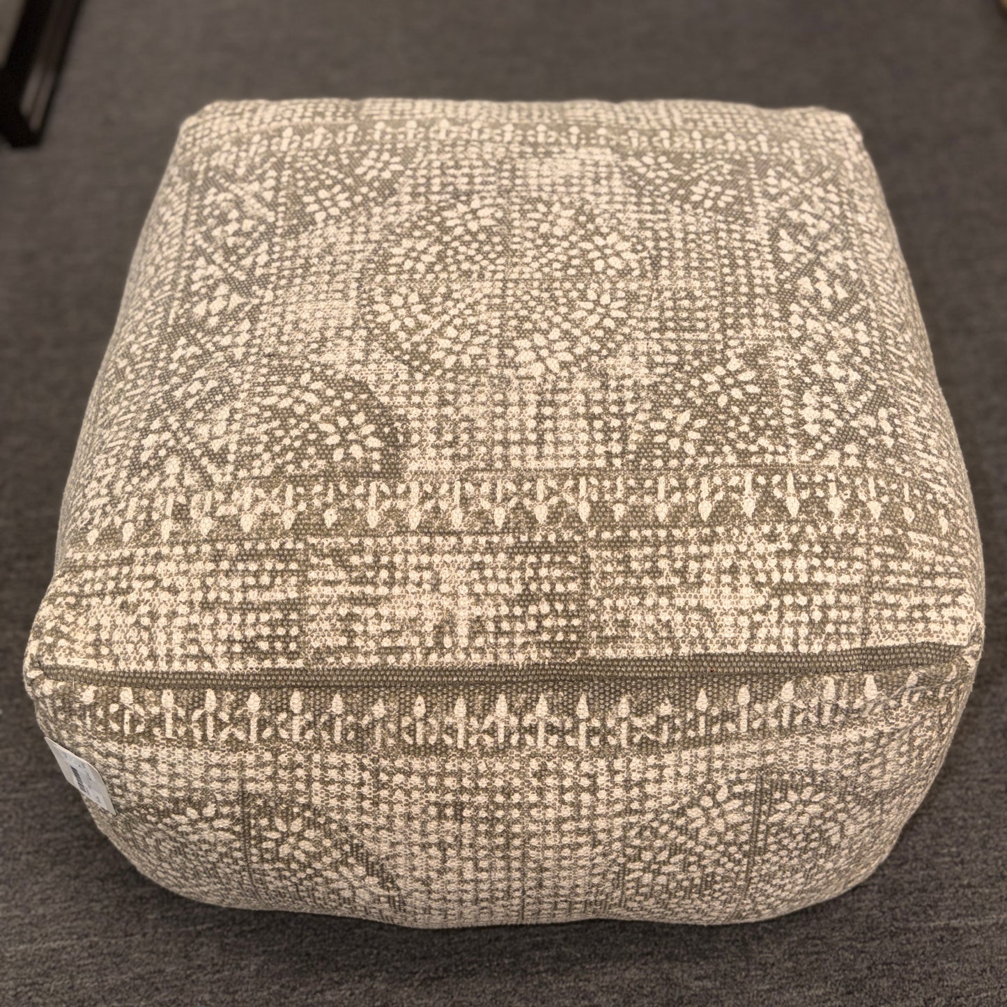 Textured square ottoman on a dark surface