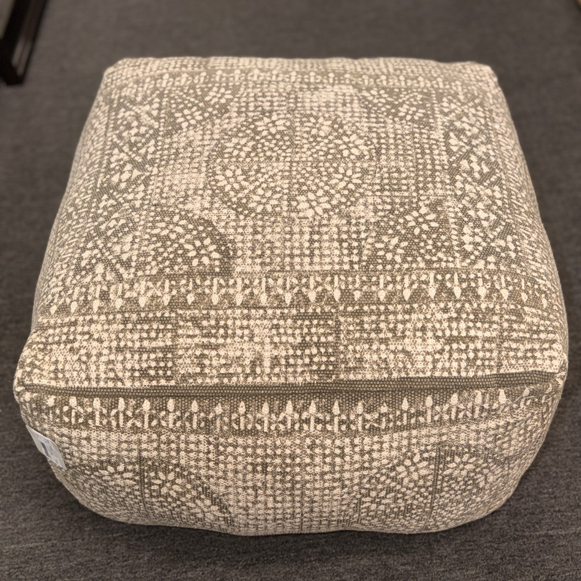 Textured square ottoman on a dark surface