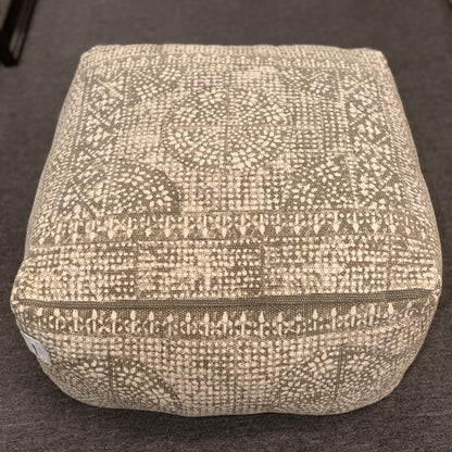 Textured square ottoman on a dark surface