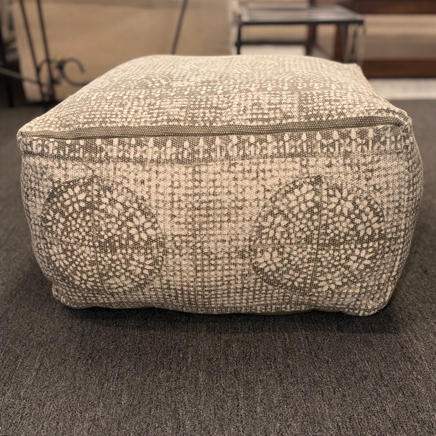 Textured ottoman on a carpeted floor with blurred background