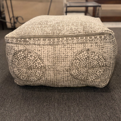 Textured ottoman on a carpeted floor with blurred background