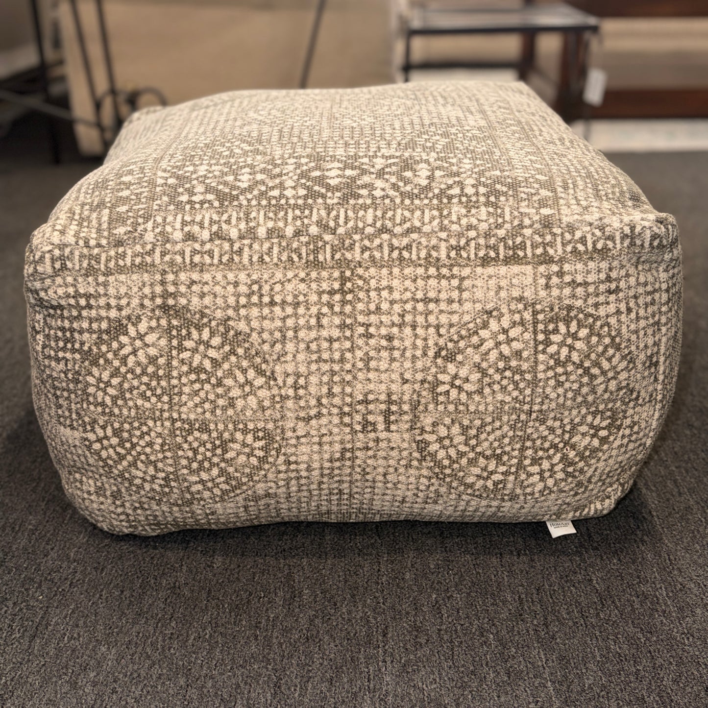 Textured ottoman on a carpeted floor with blurred background