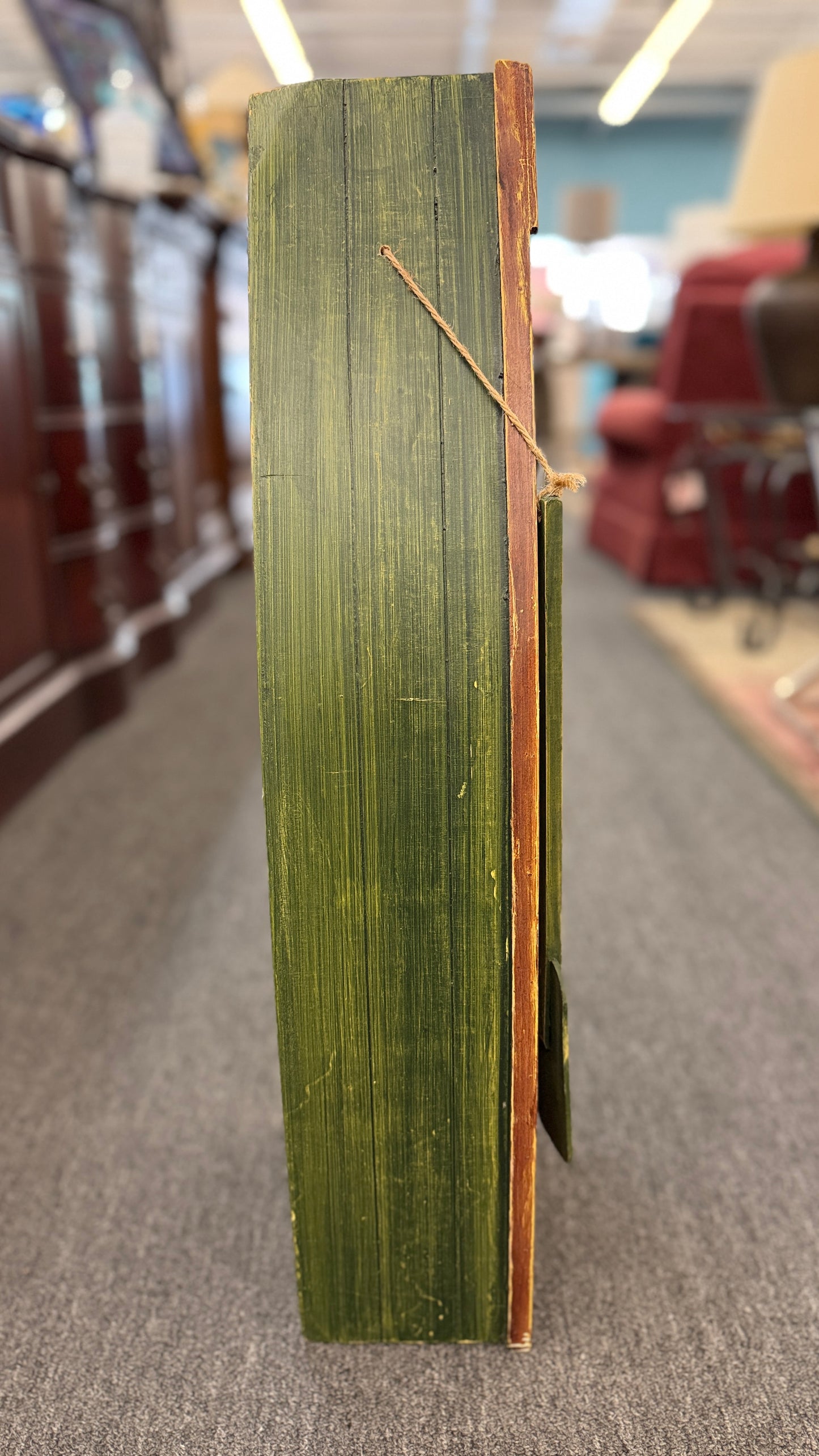 Green book with a wooden cover on a gray floor