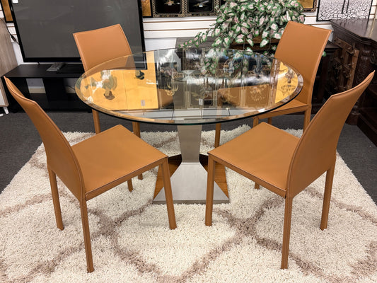 Round glass dining table with four brown chairs on a textured rug.