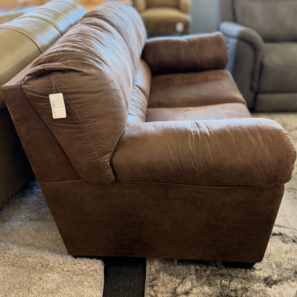 Brown sofa with a visible tag in a room with other furniture.