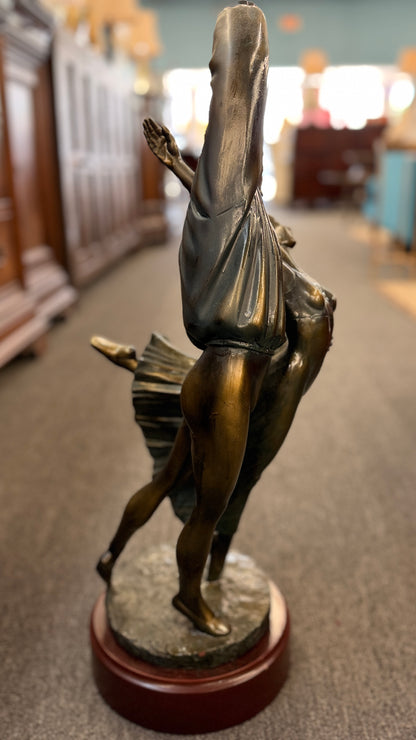Bronze sculpture of two dancers on a wooden base in a store setting
