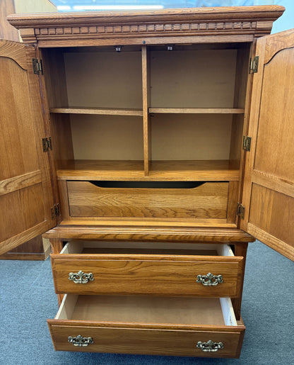 Traditional oak wood armoire and wardrobe chest featuring two doors and two lower drawers at 2nd Debut Houston consignment showroom