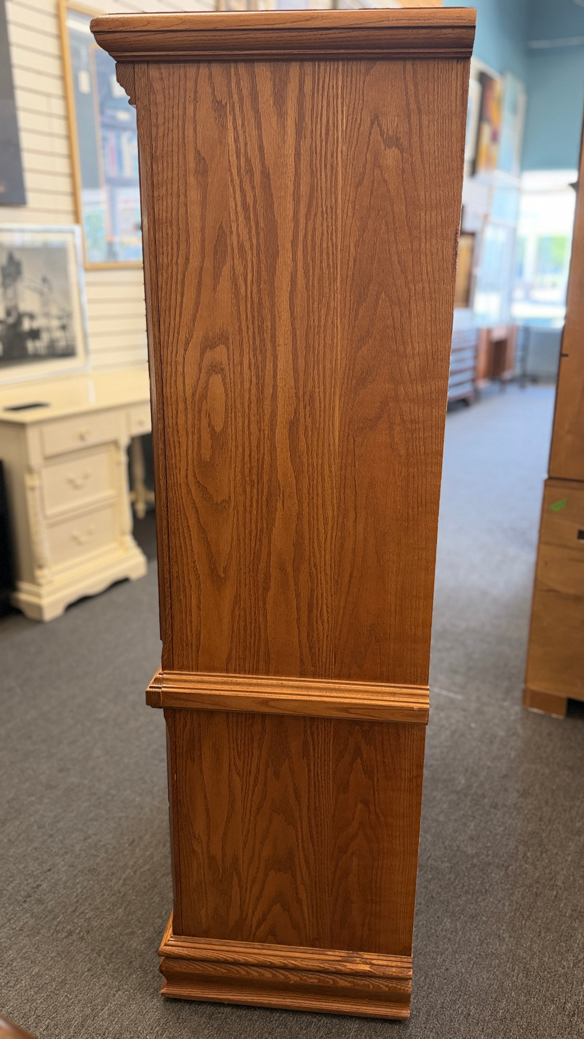 Wooden pedestal or stand in a store setting with other furniture items.