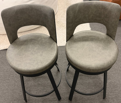 Two gray cushioned stools with black metal legs on a gray floor.