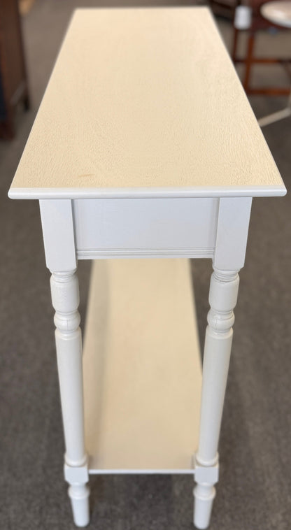 Small white table with a beige top on a gray floor.