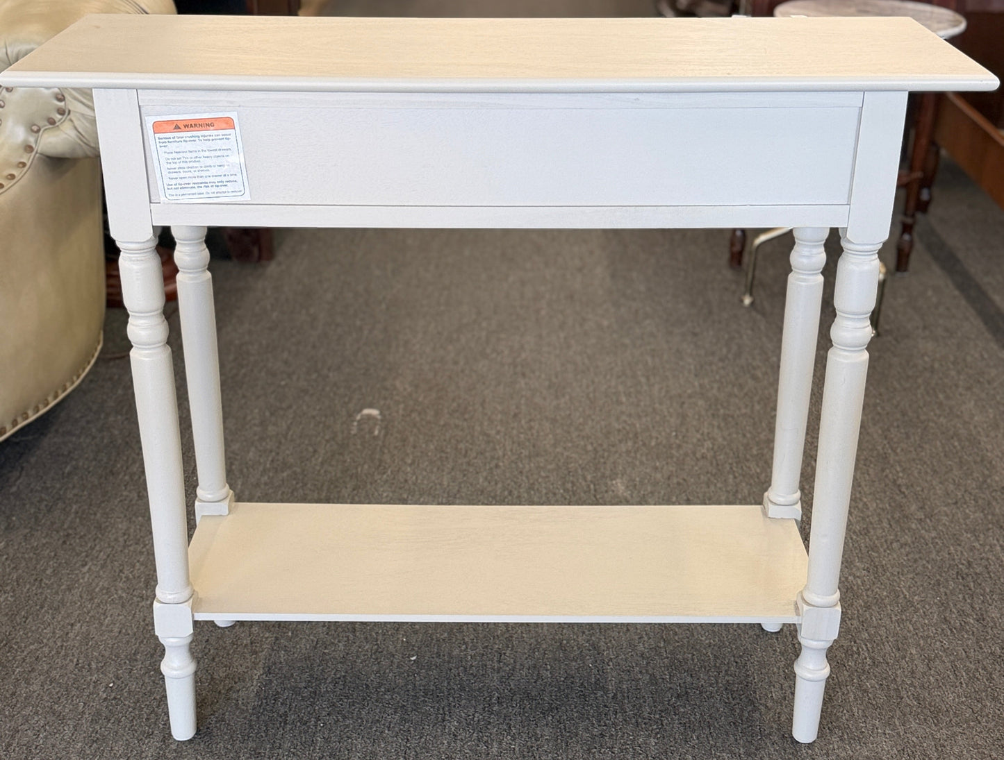 White console table with beige top and shelf in a store setting