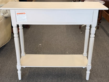 White console table with beige top and shelf in a store setting