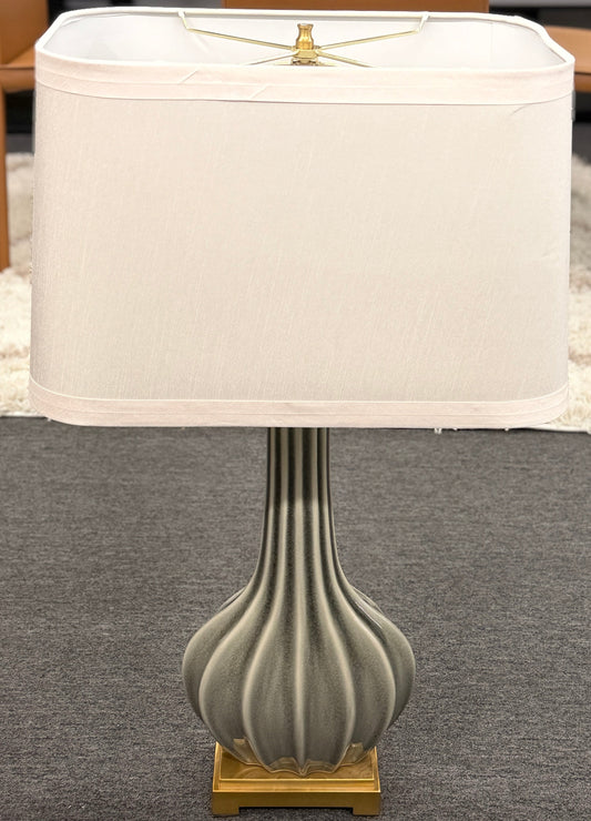 Table lamp with ribbed gray base and white shade on a gray surface.