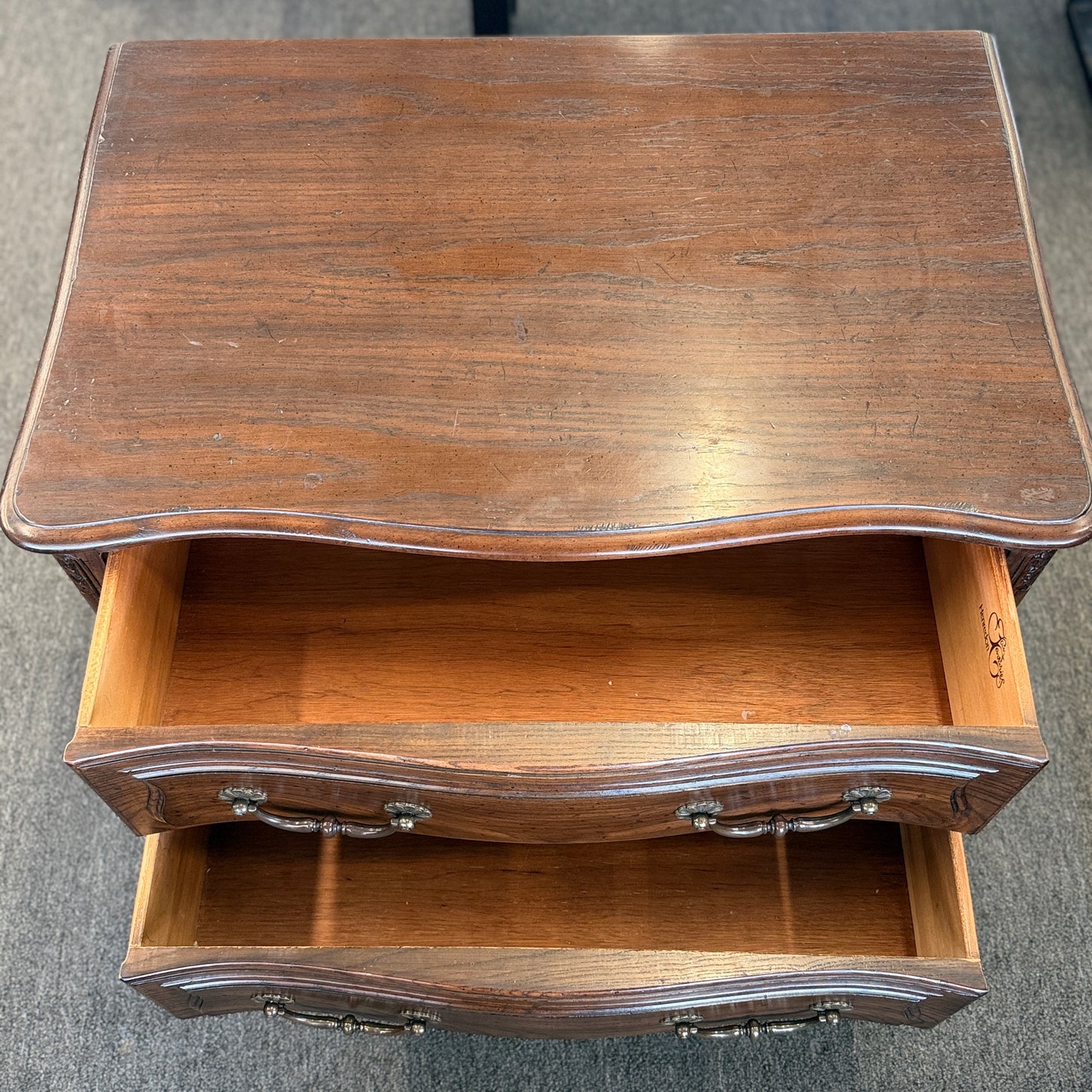 Wooden side table with an open drawer on a gray floor