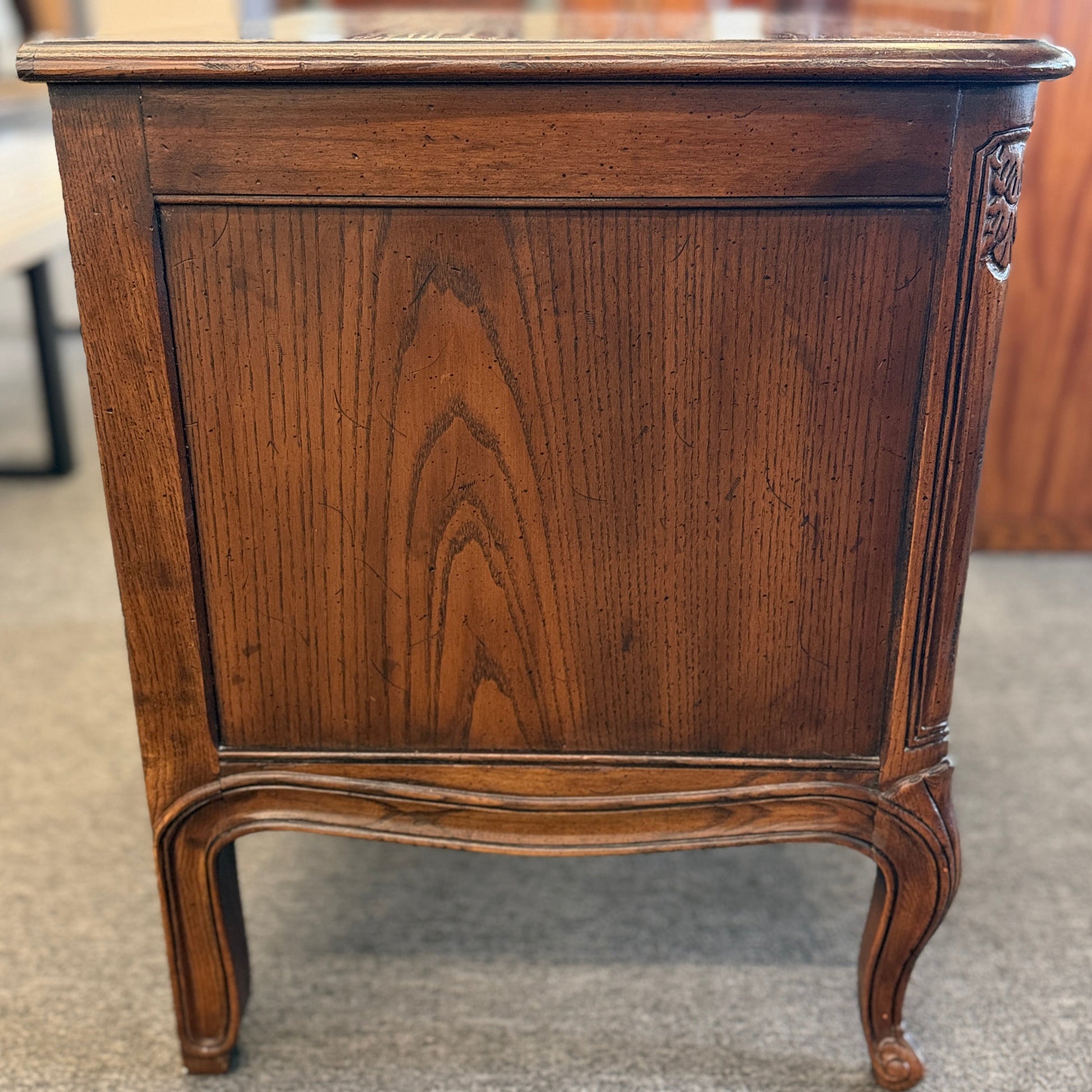 Wooden sideboard with a rich brown finish on a carpeted floor.