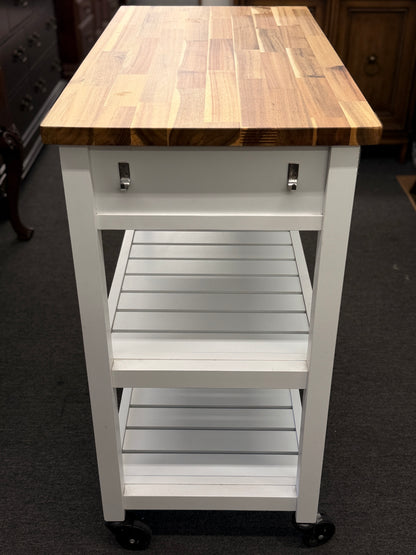 White kitchen cart with wooden top on a carpeted floor