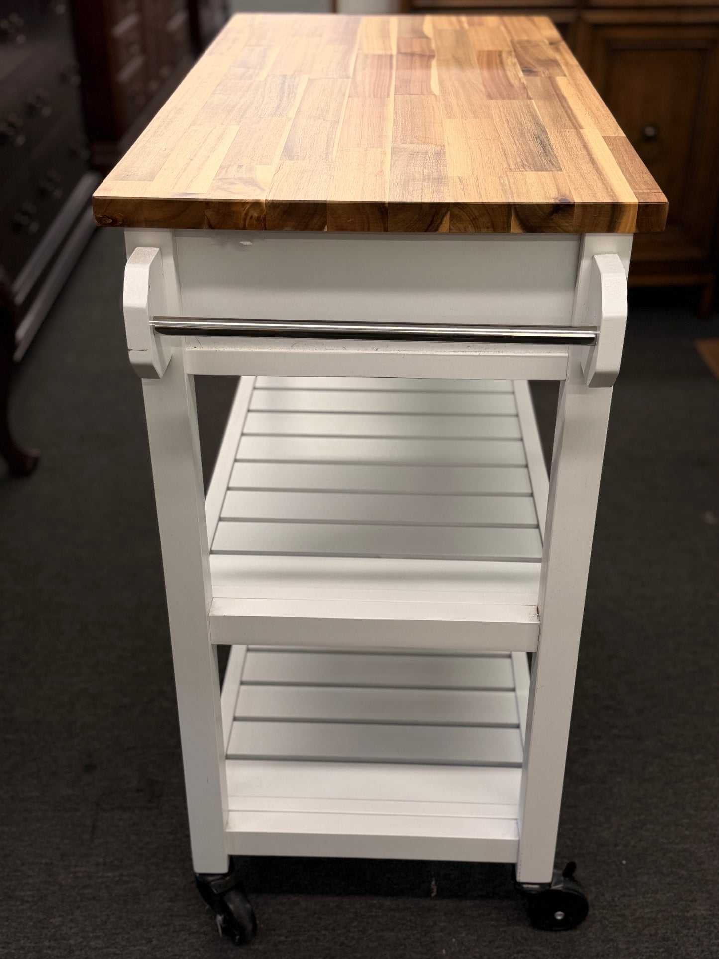 Kitchen island cart with wooden top and metal frame on a dark floor.